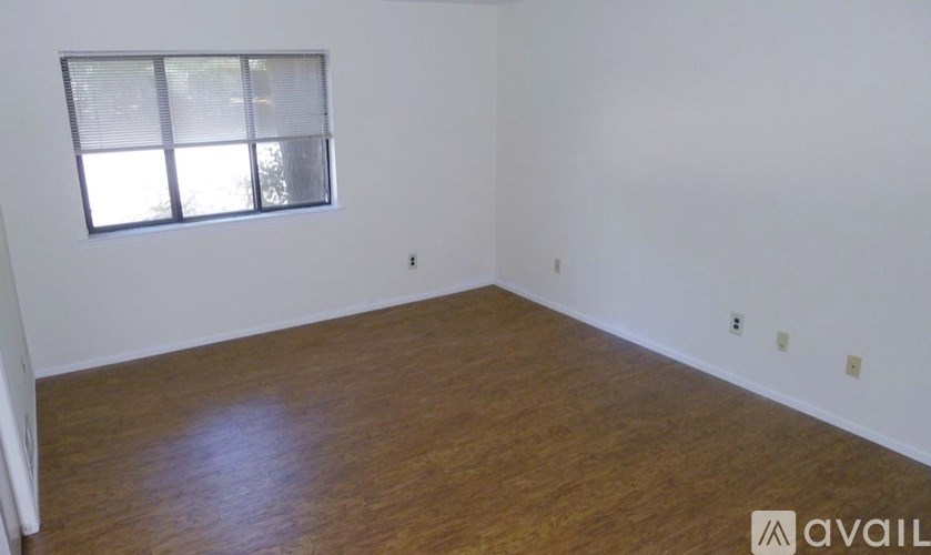 A room with wooden flooring and a window with blinds.