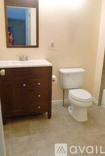 A bathroom with a toilet, sink, and mirror.