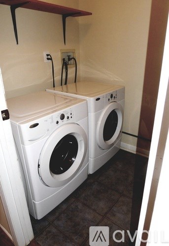 Two white front loading washing machines in a small laundry room.