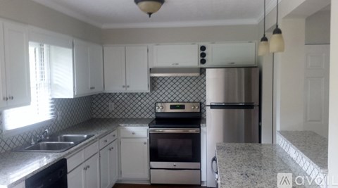 A kitchen with white cabinets and a granite counter top.