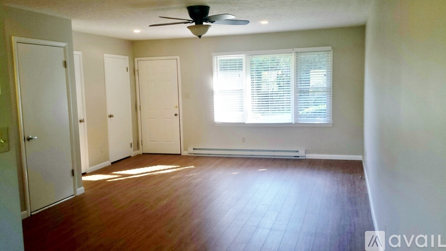 A room with a fan, wooden floors, and three doors.