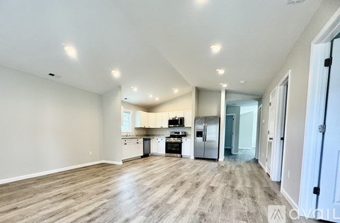 A spacious kitchen with white cabinets and a wooden floor.