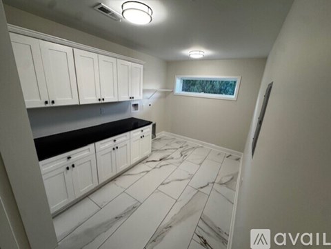 A kitchen with white cabinets and a black countertop.