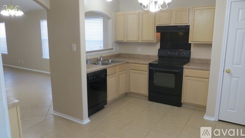 A kitchen with black appliances and beige cabinets.