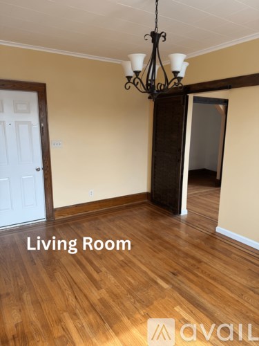 A living room with wooden floors and a chandelier.