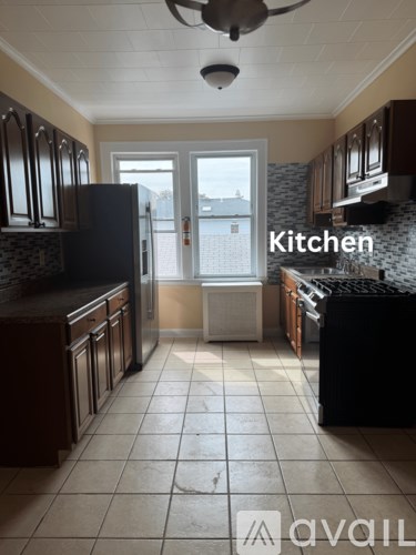 A kitchen with a black fridge and brown cabinets.