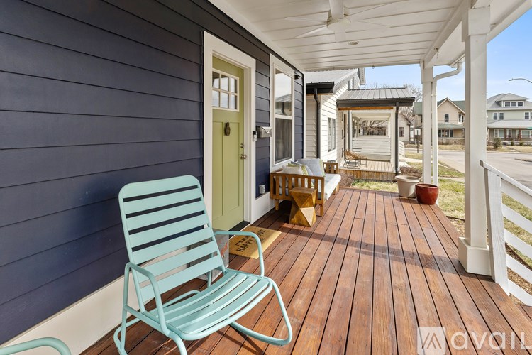 A blue chair is on a porch with a white railing.