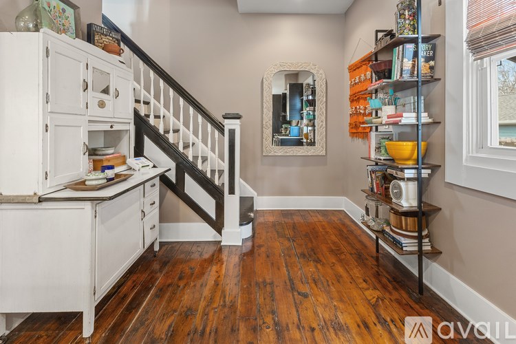 A wooden floor leads to a staircase with a white cabinet underneath.