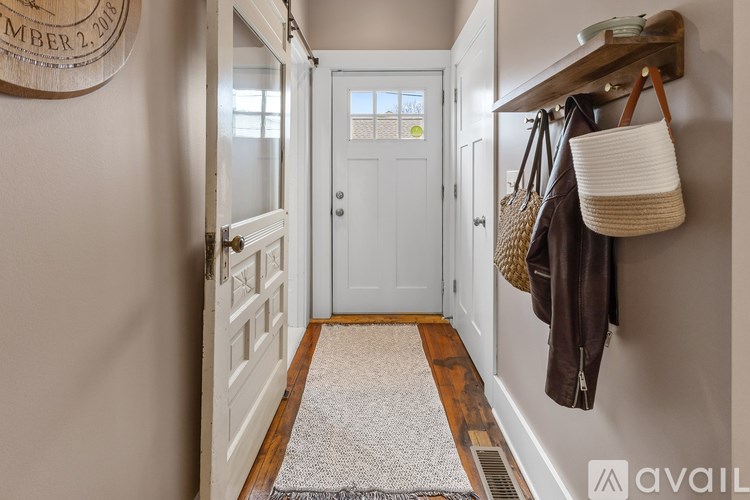 A hallway with a white door and a wooden floor.