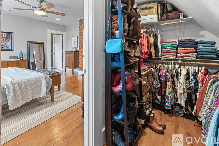 A room with a bed and a closet full of clothes.