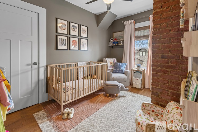 A baby room with a crib, a chair and a wall with pictures.