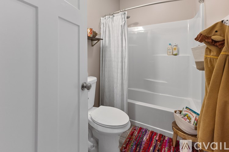 A bathroom with a toilet, a shower curtain, and a towel rack.