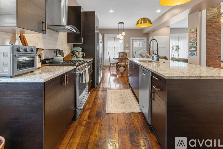 A modern kitchen with dark wood floors and stainless steel appliances.