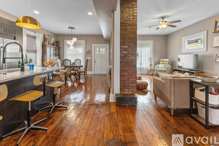 A kitchen with wooden floors and a brick column.
