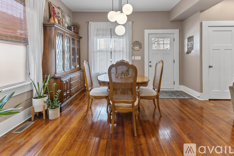 A dining room with wooden floors and a table set with chairs.