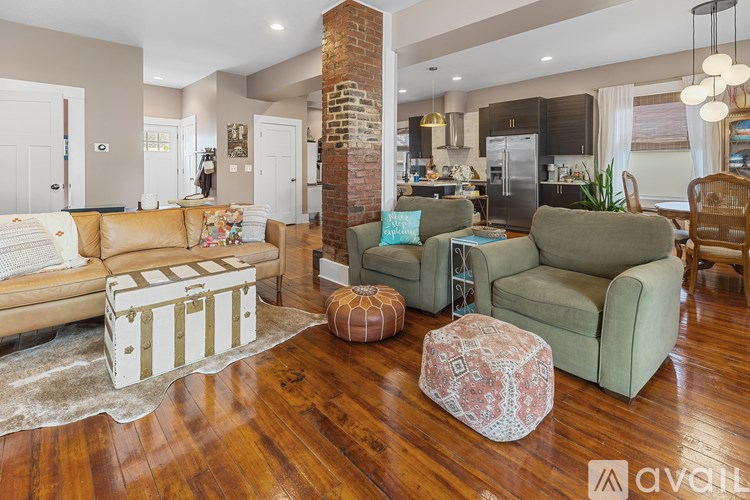 A living room with a white couch, a green chair, and a wooden floor.