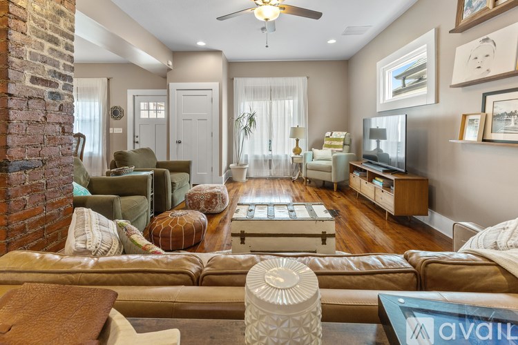 A living room with a brick column and a brown couch.