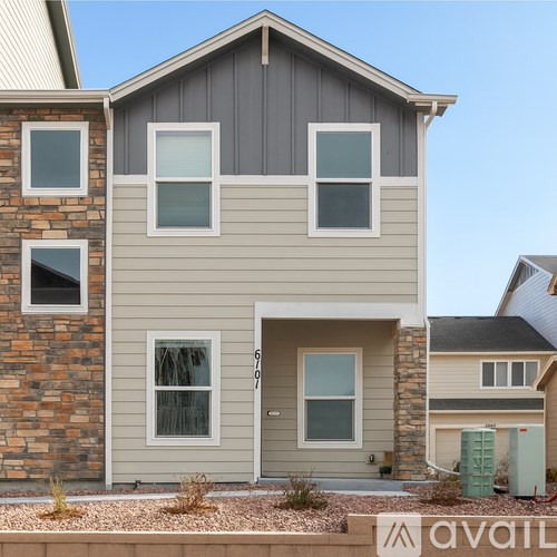 A modern house with a grey front and a stone pillar.
