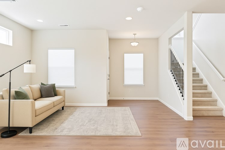 A living room with a beige couch and a staircase.