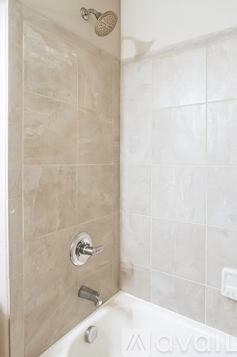 A shower with a white tub and a wall of tiles.