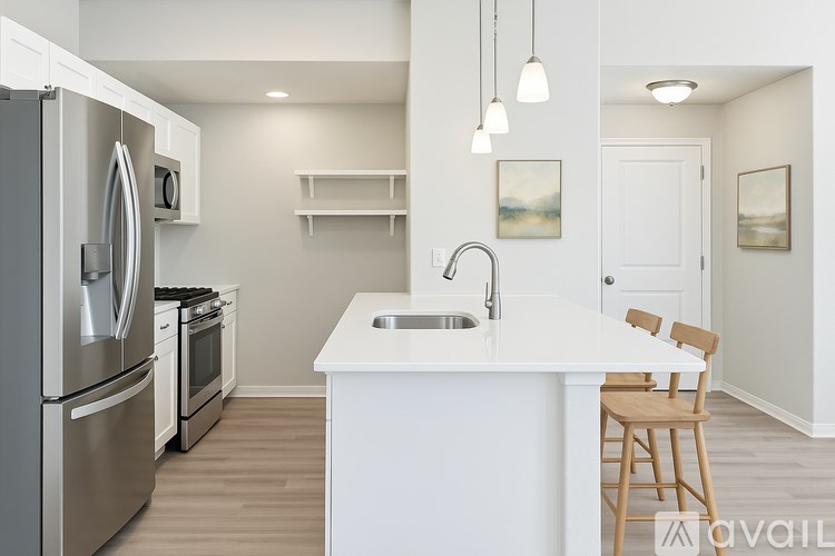 A modern kitchen with a white countertop and stainless steel appliances.