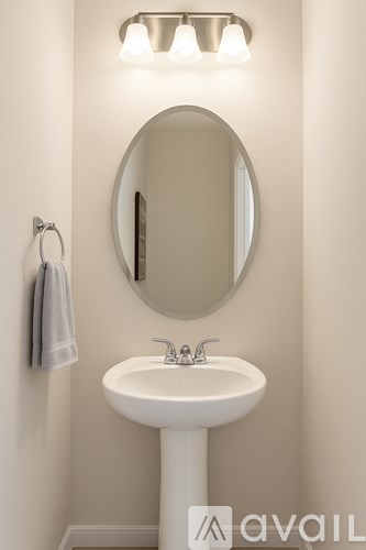 A white pedestal sink with a round mirror above it.