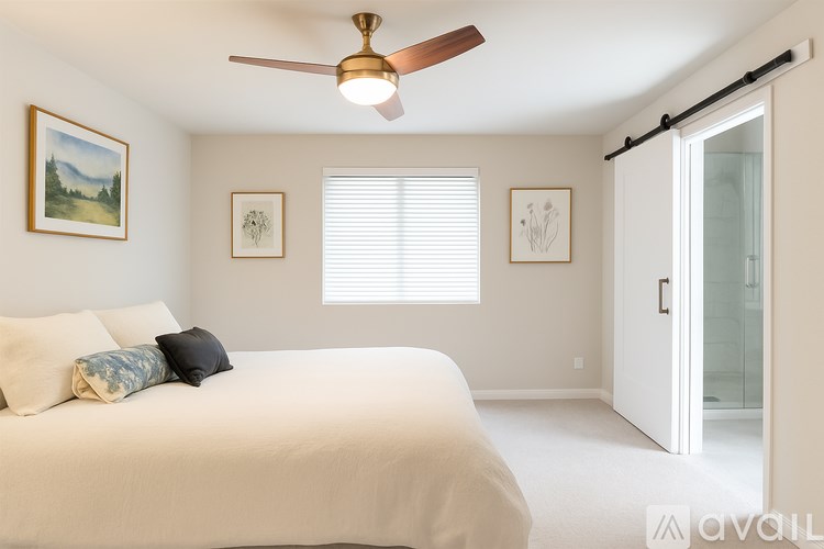 A bedroom with a bed, a ceiling fan, and pictures on the wall.