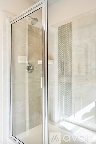 A glass shower door with a handle and a shower head.