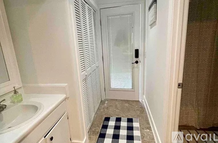 A bathroom with a sink, mirror, and a checkered rug.