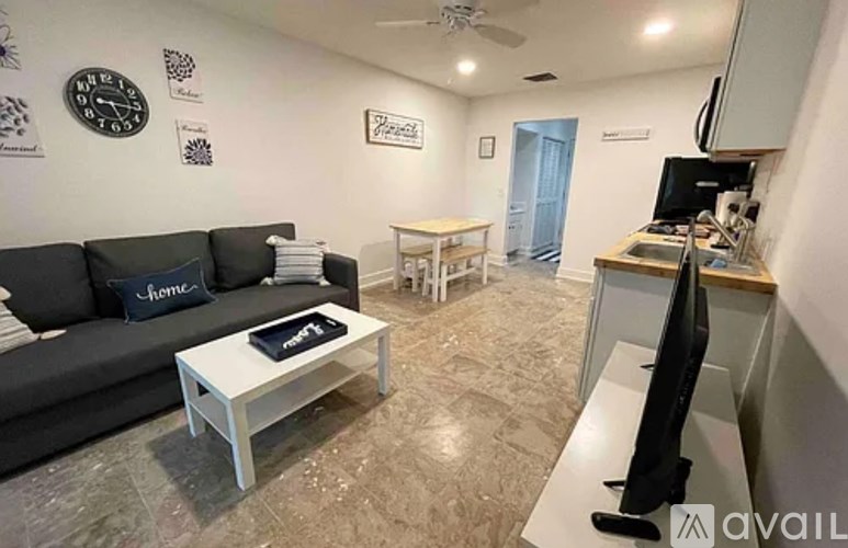 A living room with a black couch, a white coffee table, and a flat screen TV.