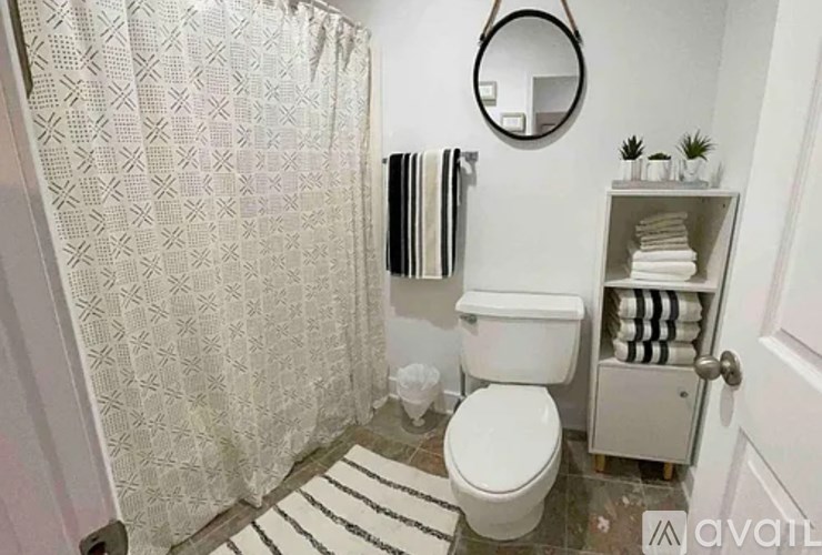 A bathroom with a toilet, a shower curtain, and a towel rack.