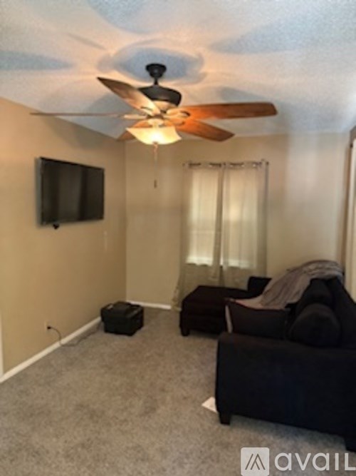 A living room with a ceiling fan and a flat screen TV.