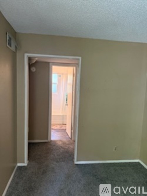 A room with a carpeted floor and a doorway leading to another room.