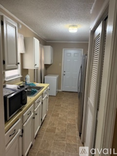 A kitchen with white cabinets and a microwave on the counter.
