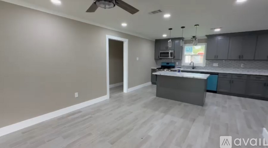 A modern kitchen with a large island and a ceiling fan.