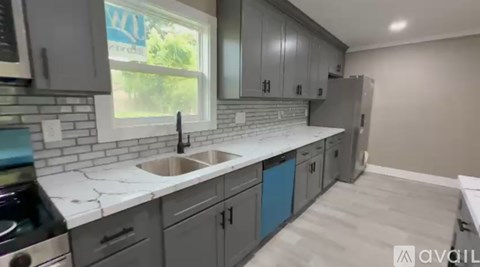 A kitchen with grey cabinets and a white countertop.