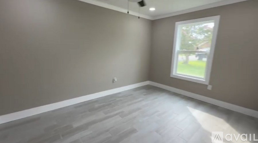 A room with a grey floor and a window showing a green lawn outside.