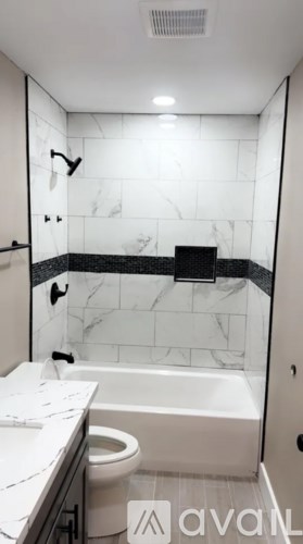 A bathroom with a marble tile wall and a walk-in shower.