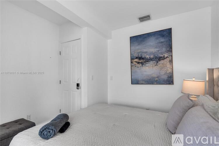 A bedroom with a large bed and a painting on the wall.