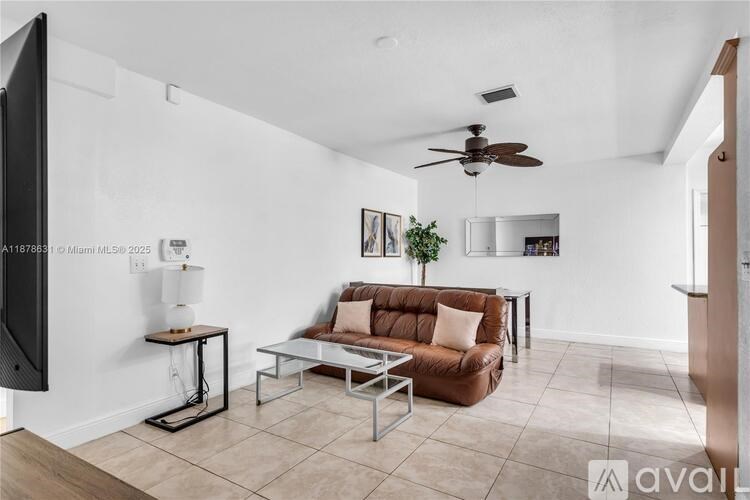 A living room with a brown couch and a television mounted on the wall.