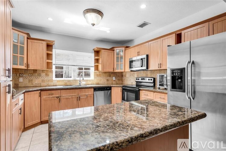 A kitchen with a granite countertop and stainless steel appliances.