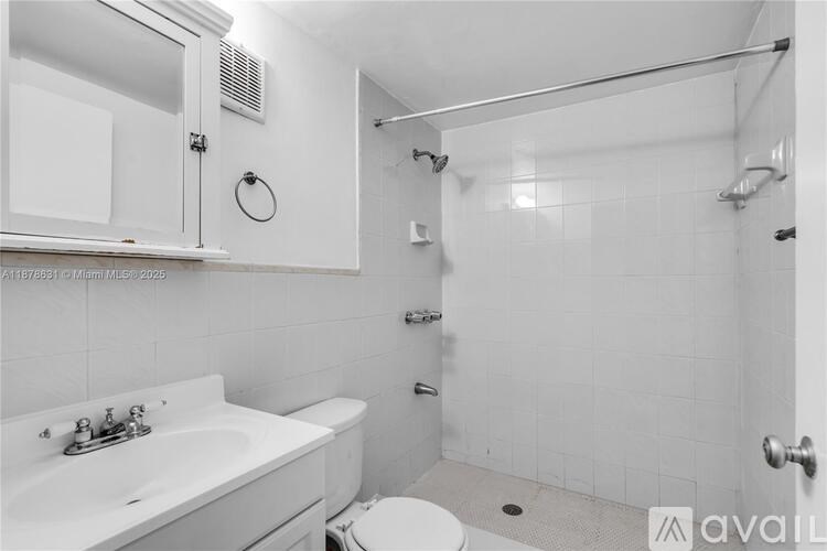 A white bathroom with a toilet, sink, and shower.