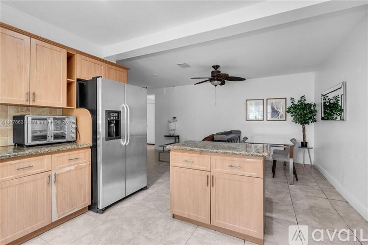 A kitchen with wooden cabinets and a stainless steel refrigerator.