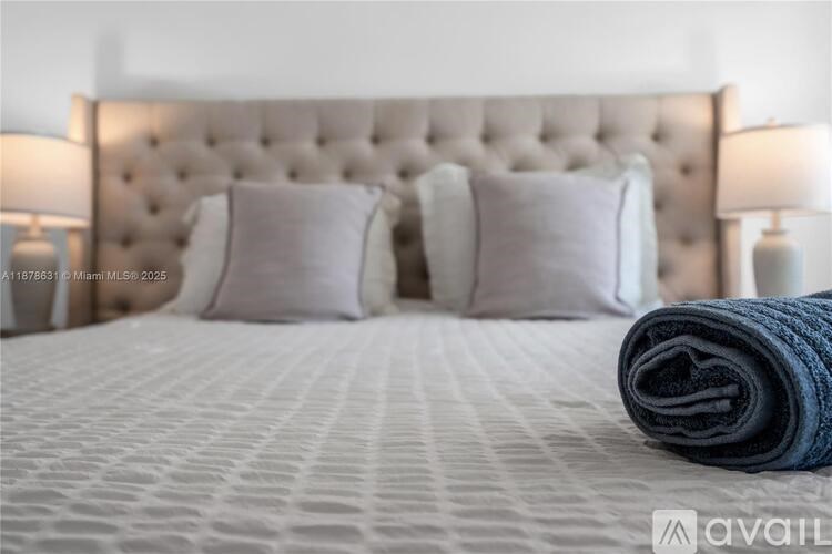 A bed with a tufted headboard and a rolled-up blanket on top.