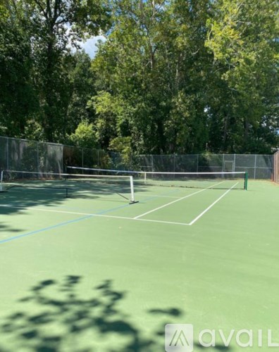 A tennis court surrounded by trees and a fence.
