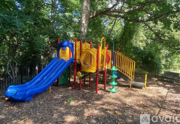 A playground with a blue slide and a yellow and red climbing frame.