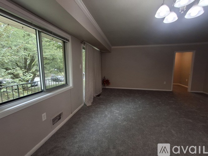 A room with a large window and a door is available for rent.