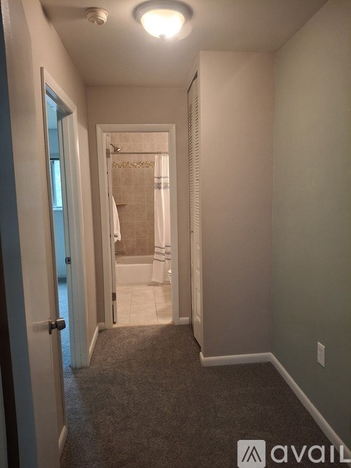A hallway with a carpeted floor and a door leading to a bathroom.
