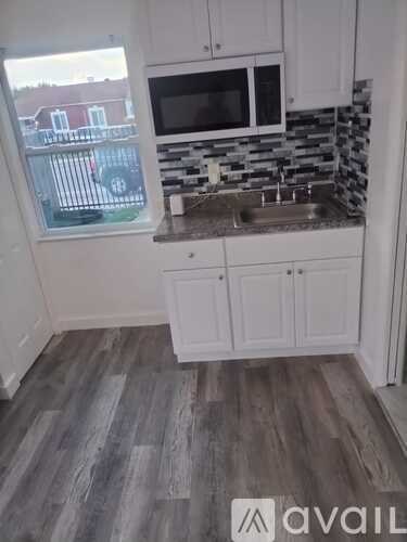 A kitchen with white cabinets and a window overlooking a parking lot.