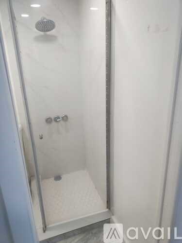 A shower stall with a glass door and a drain.